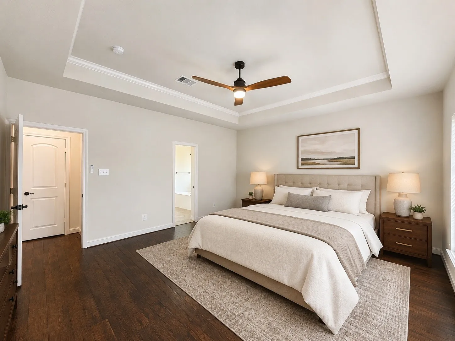 Tray ceiling with crown molding, wood-finish flooring, two-panel interior doors, and a ceiling fan with integrated lighting
