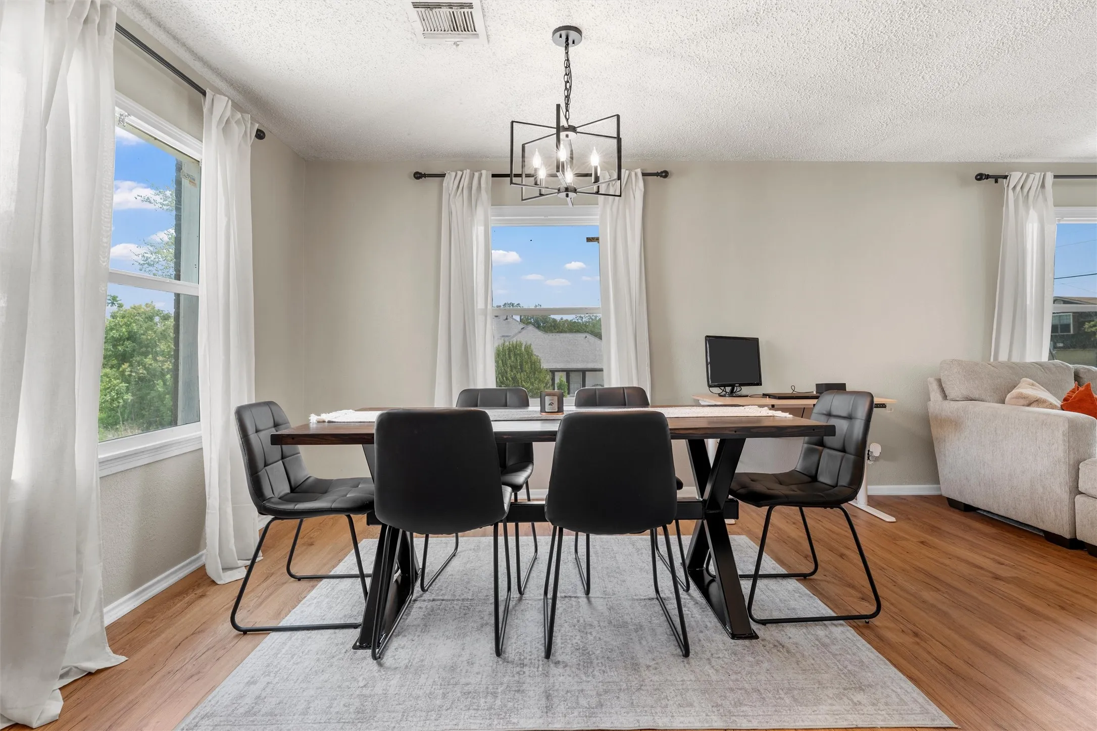 Wood-finish flooring, abundant natural light, and a modern chandelier