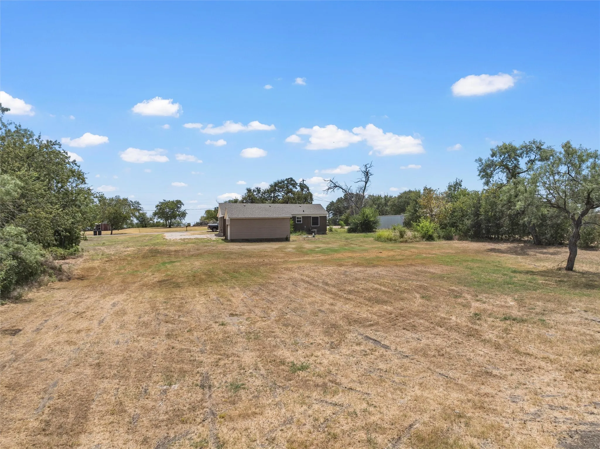 Expansive undeveloped land featuring mature trees and a clear sky