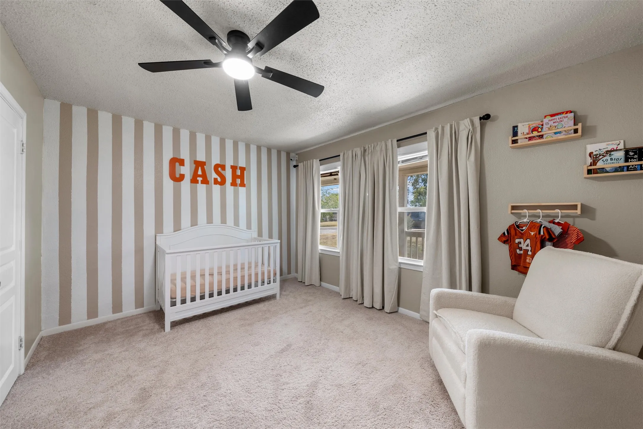 Textured carpeting, multiple windows, ceiling fan with integrated lighting, and a neutral color palette