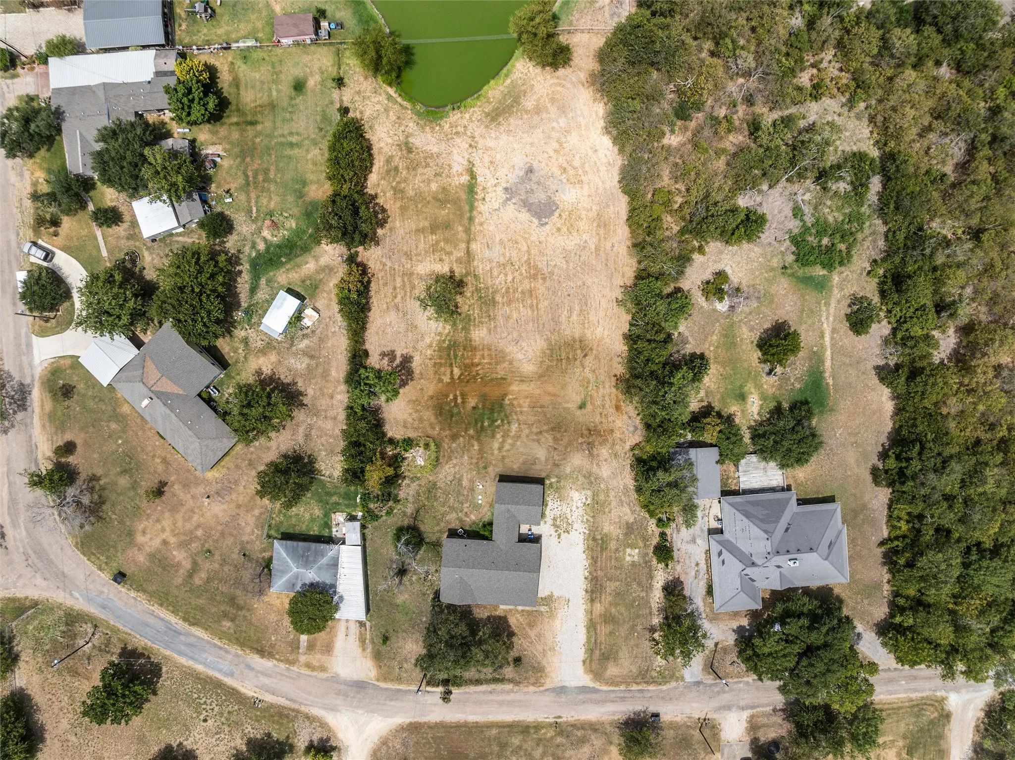 Expansive lot featuring a primary residence, a secondary structure, and a large pond