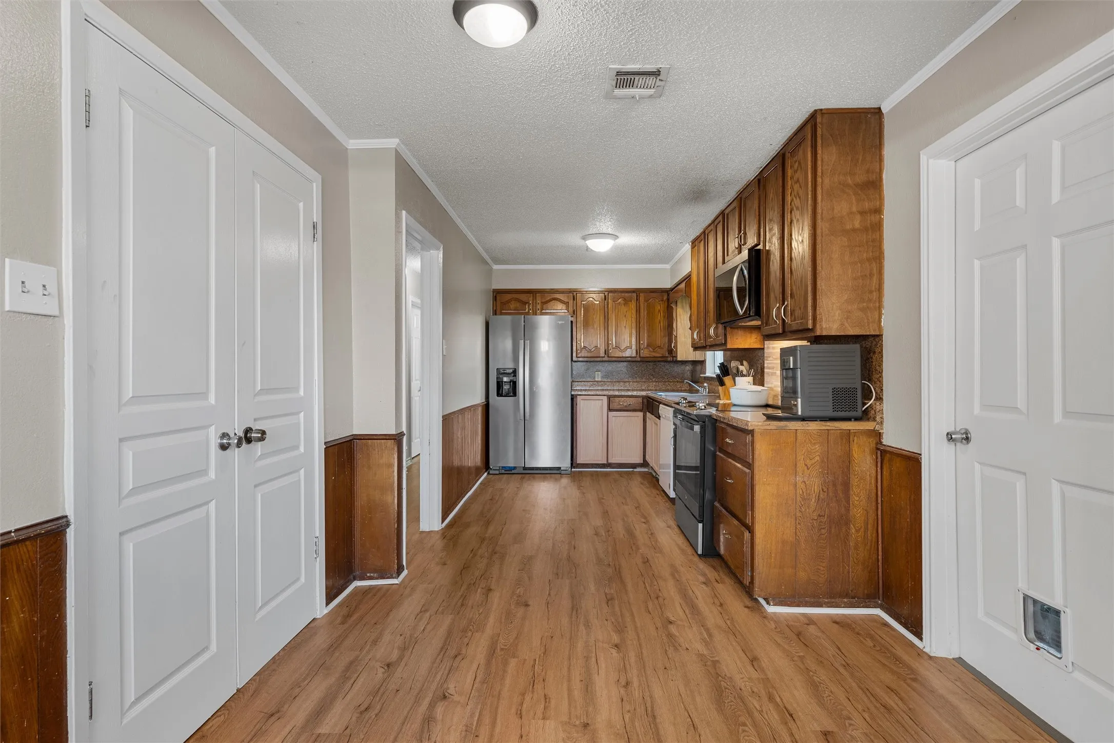 Wood-finish flooring, wood paneling, wood cabinetry, built-in stainless steel appliances, and ceiling-mounted lighting