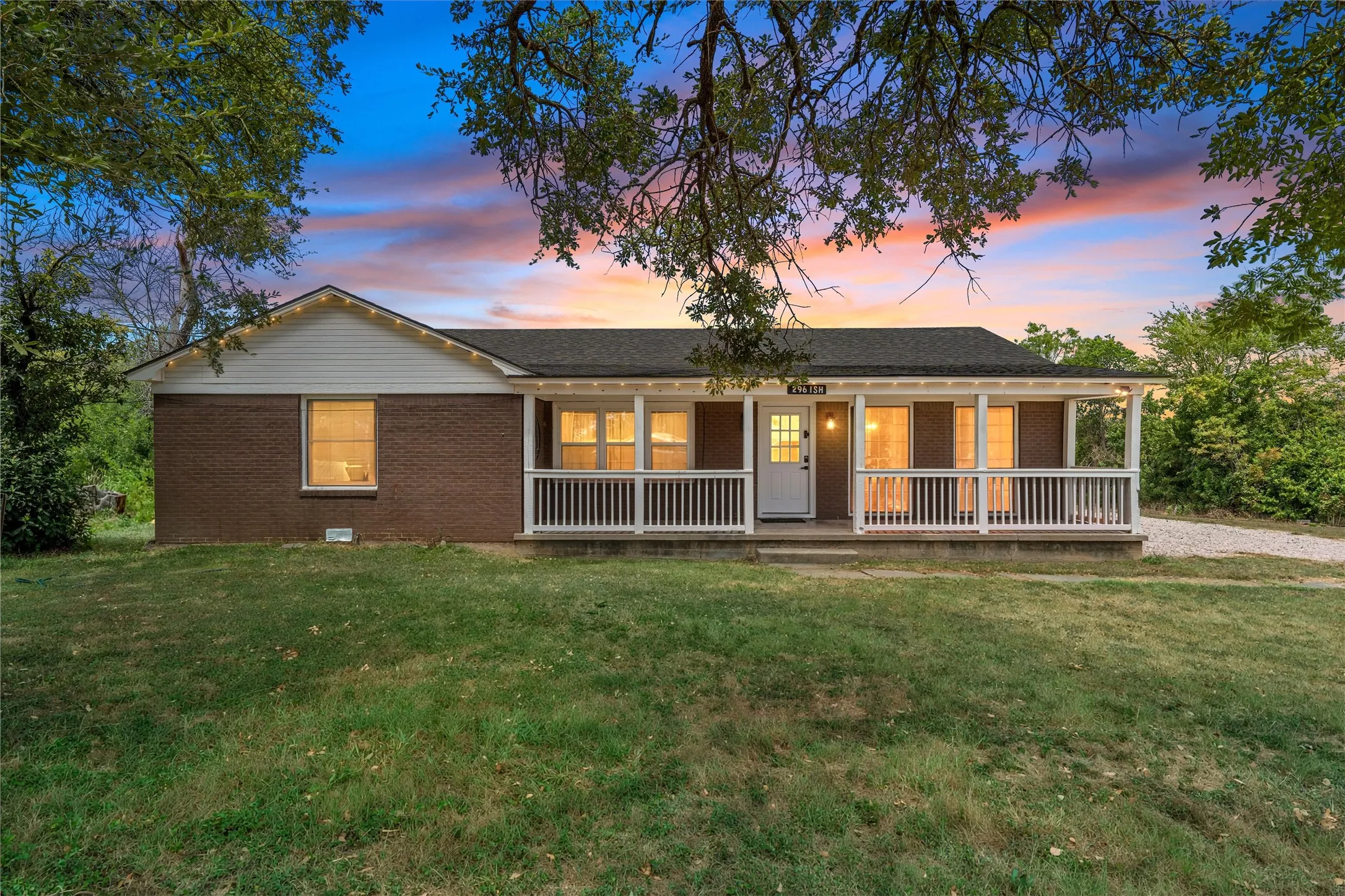 Brick exterior with white siding accents and a covered front porch featuring white railings