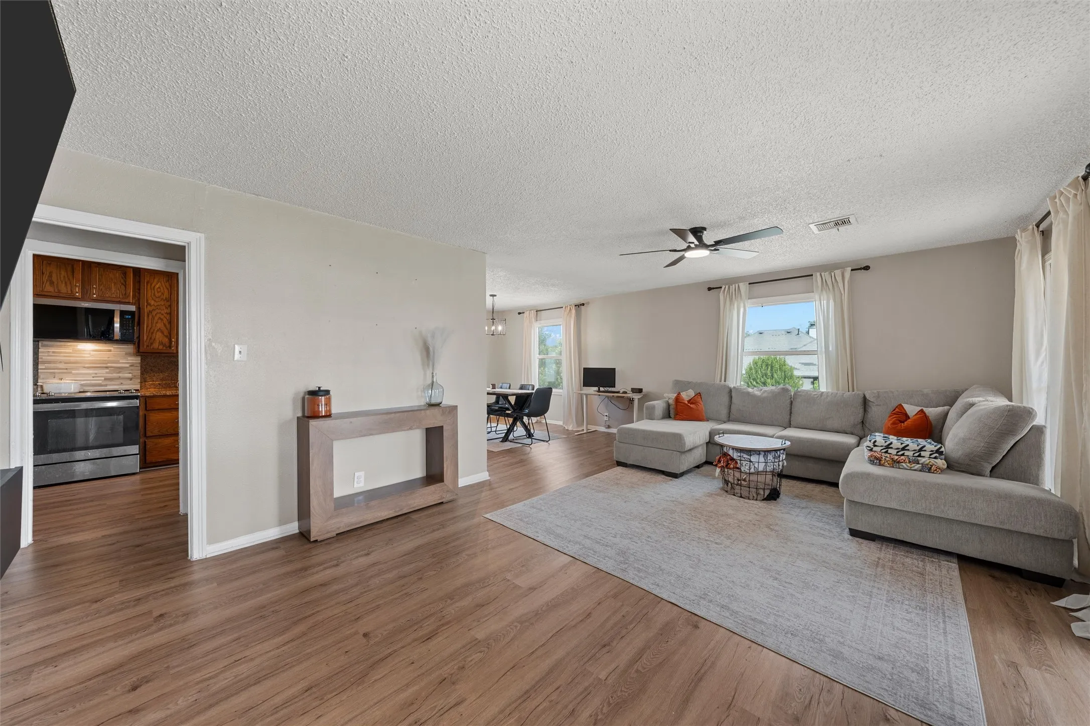 Wood-finish flooring throughout, light-toned wall paint, and a ceiling fan with integrated lighting