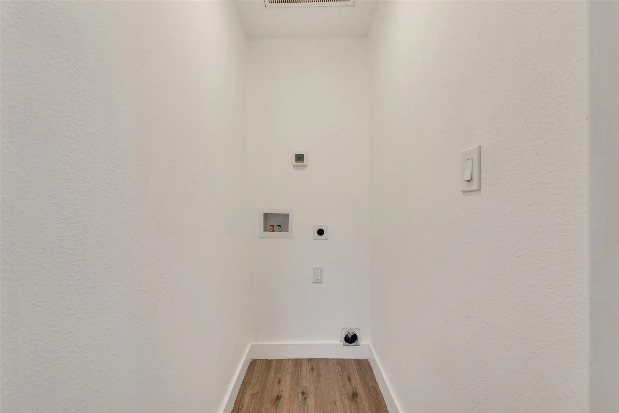 Dedicated utility space featuring wood-finish flooring
