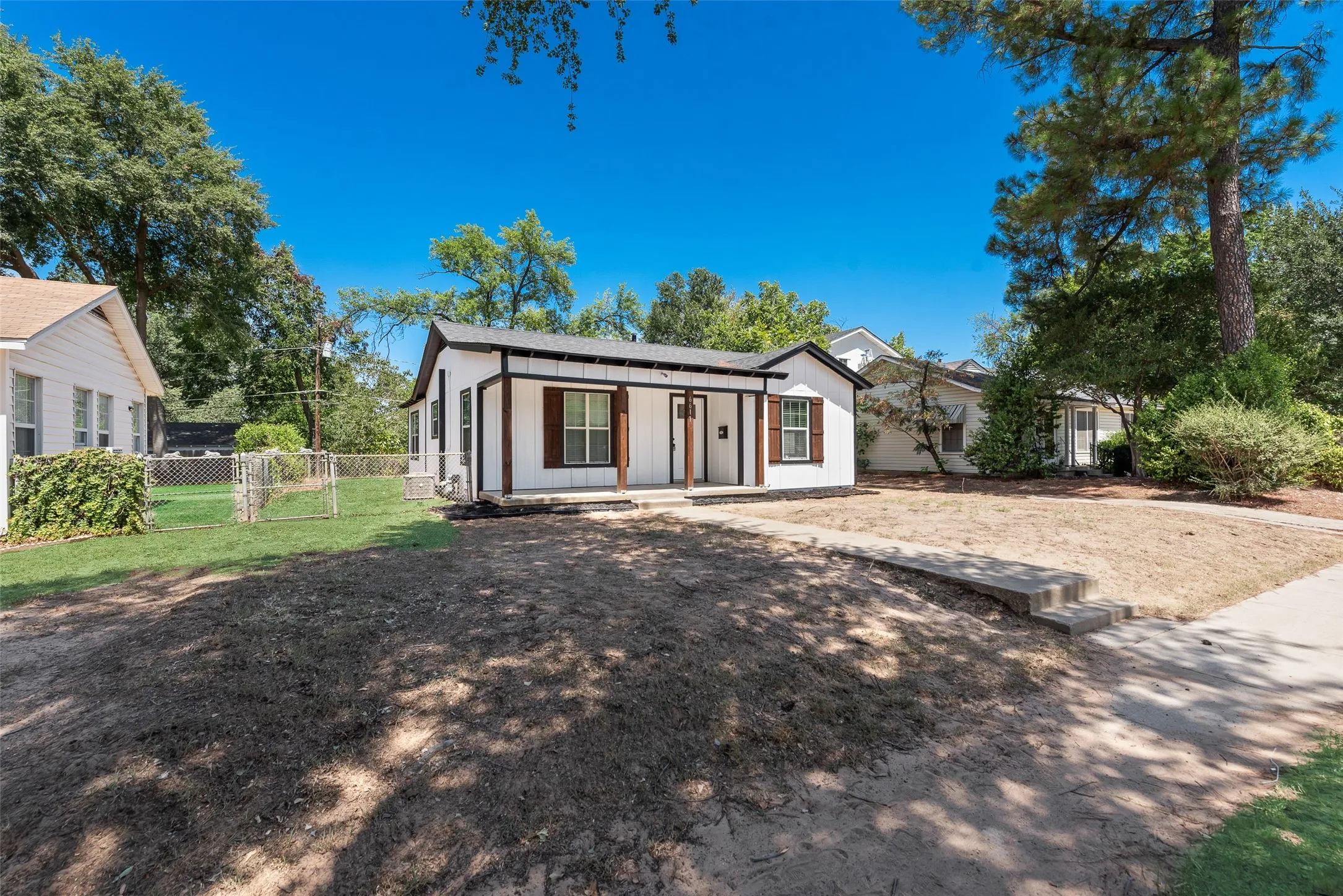 White exterior siding with dark trim accents, covered front porch, and brown window shutters