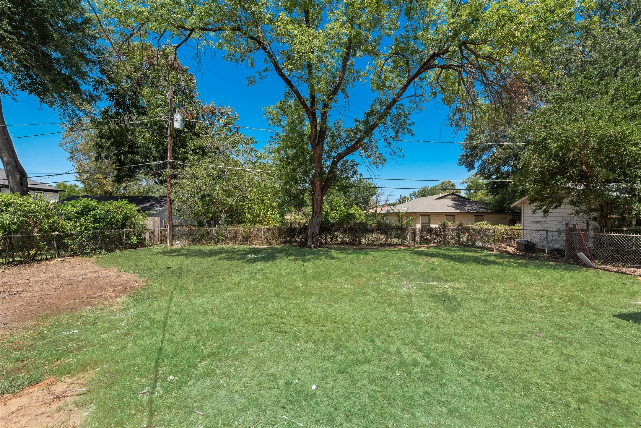 Expansive lawn area with mature trees and perimeter fencing