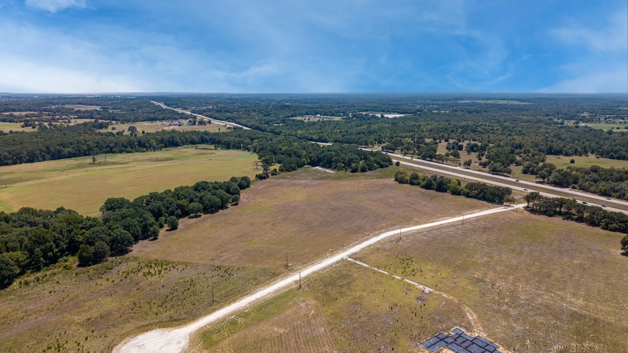 Expansive acreage featuring a natural tree line, partial pasture, and direct access to a paved road