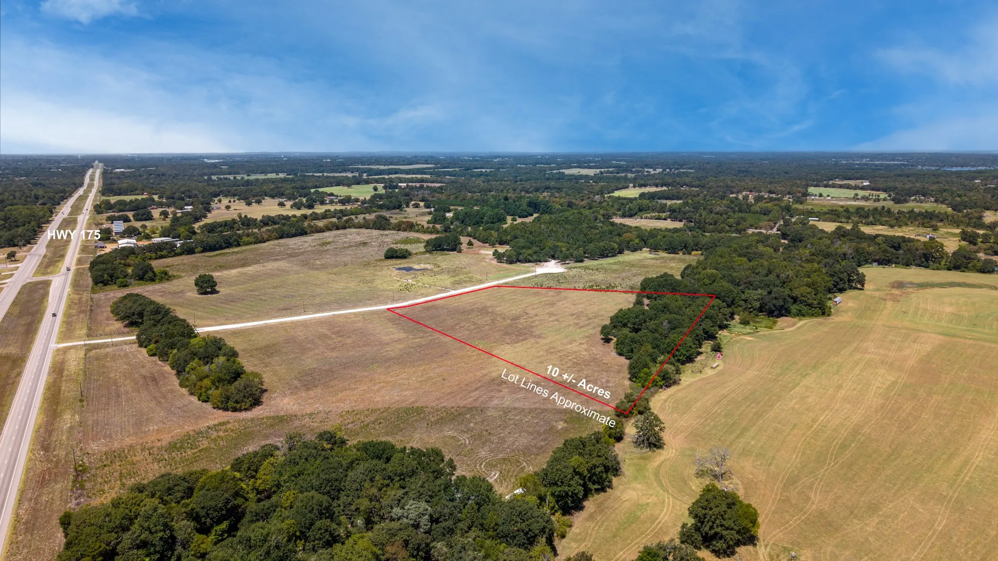 Expansive 10± acre parcel featuring varied terrain, mature trees, and direct frontage on HWY 175