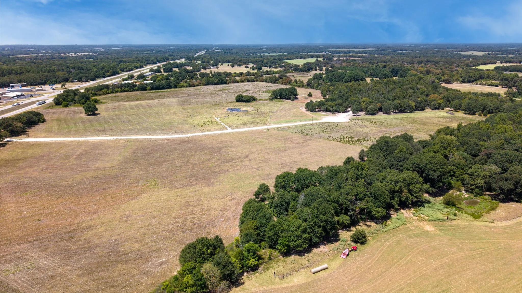 Expansive land offering a combination of open fields and mature tree lines