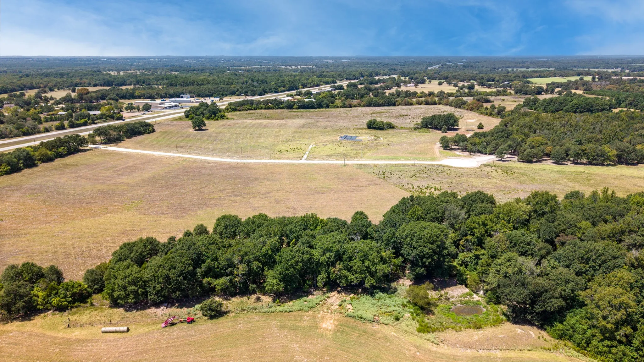 Expansive land parcel featuring wooded areas, open fields, and established access roads