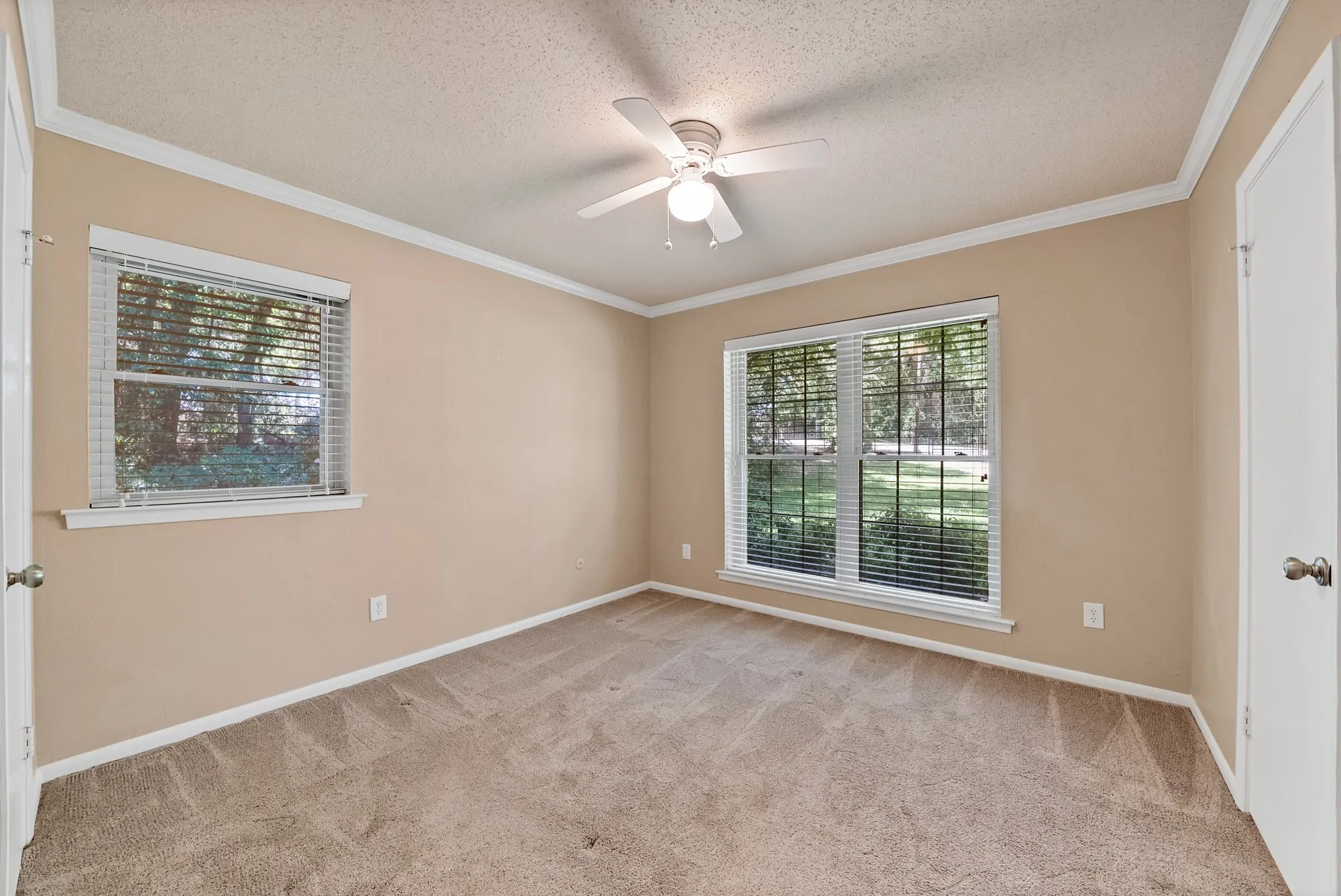 Neutral tone wall paint, carpeted flooring, crown molding, and a ceiling fan with integrated lighting