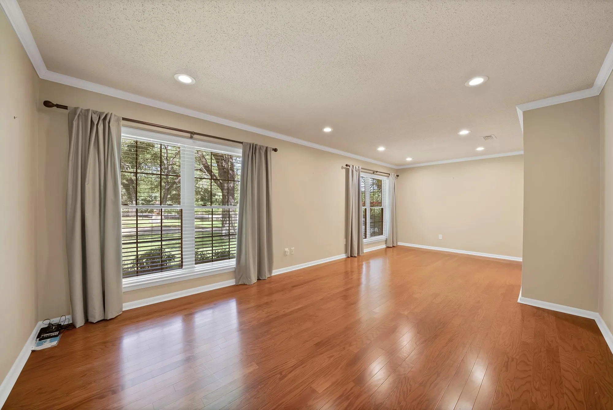 Recessed lighting, wood-finish flooring, multiple windows, crown molding, and neutral wall tones