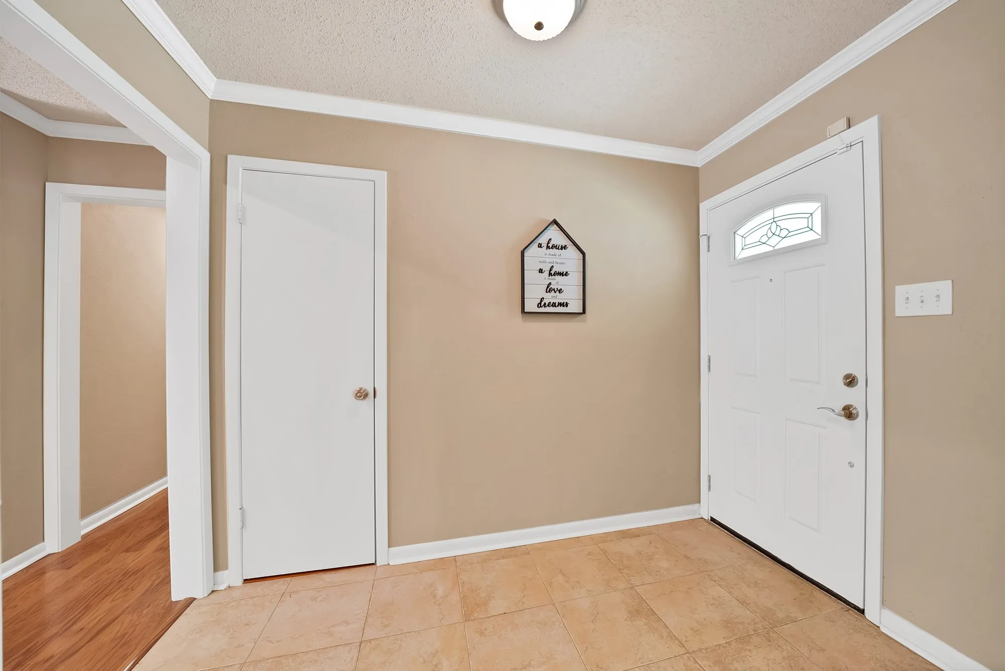 Foyer with tiled flooring, neutral wall paint, white trim, and a white entry door with decorative glass inlay