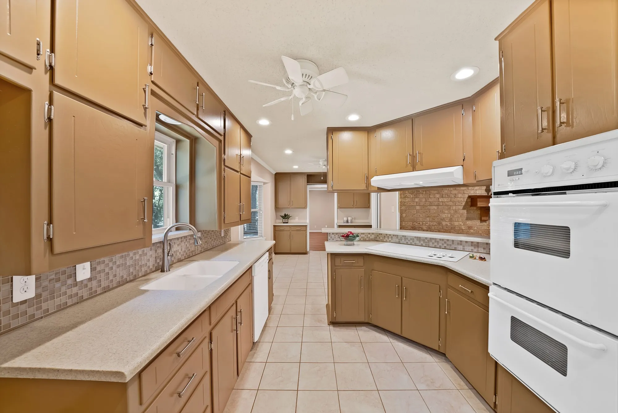 Kitchen featuring extensive cabinetry, tile flooring, a dual basin sink, integrated double ovens, and recessed lighting