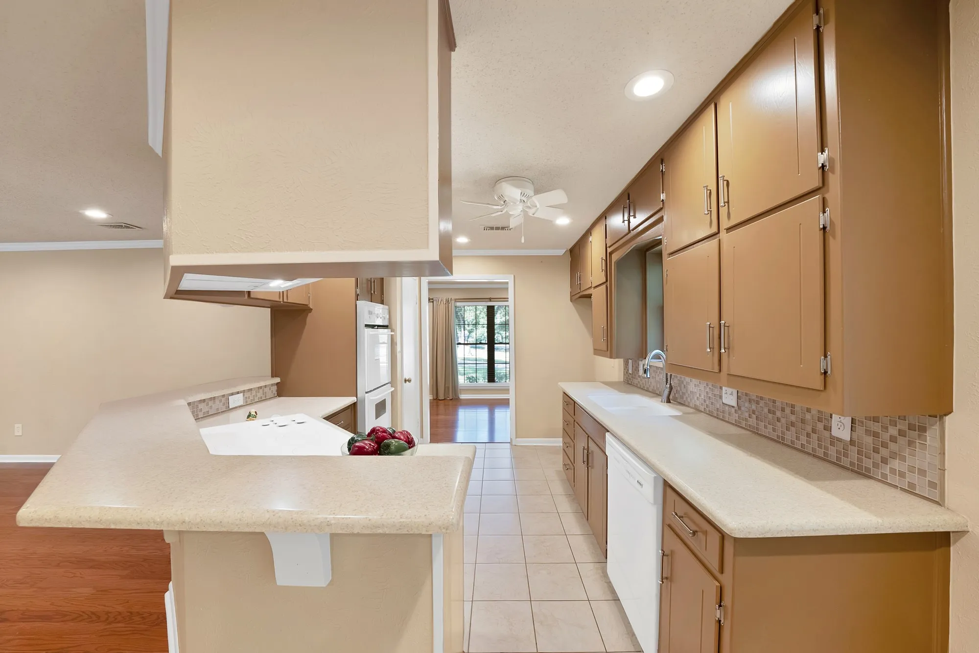 Kitchen featuring wood-finish cabinetry, tile backsplash, built-in oven, and a breakfast bar