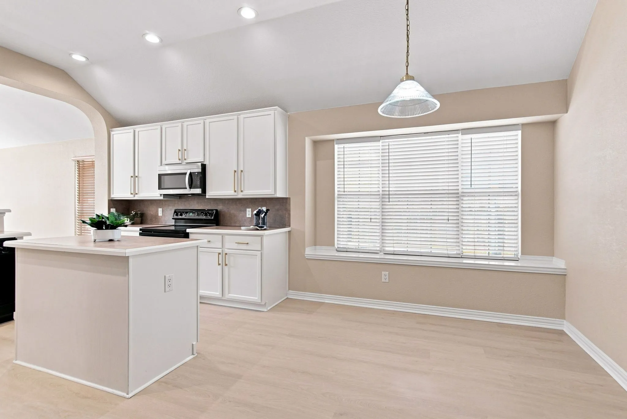 Kitchen featuring white cabinetry, light-toned wood-finish flooring, recessed lighting, and a kitchen island with a light-colored countertop