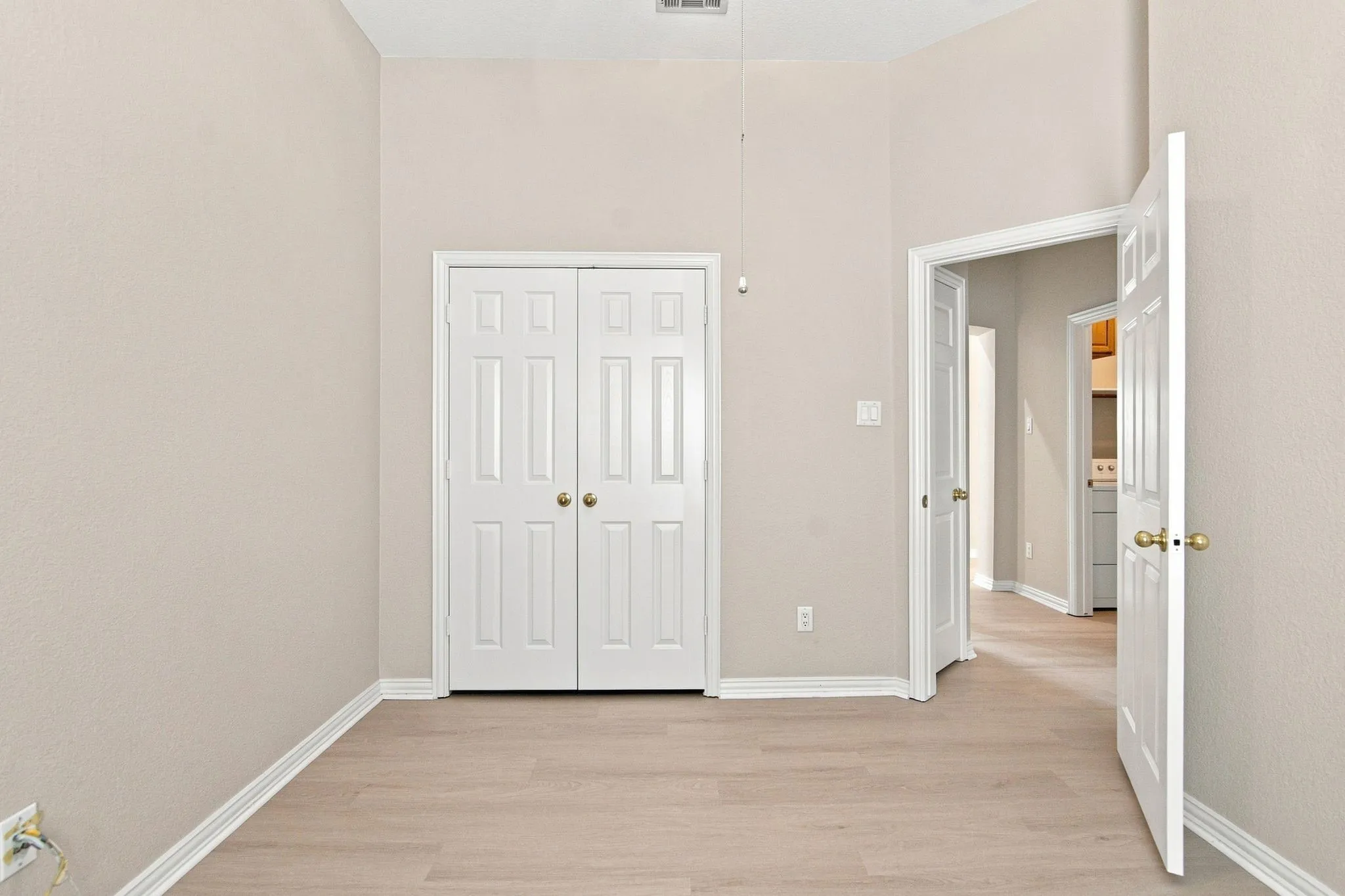 Vaulted ceiling with a ceiling fan, light wood-finish flooring, and white bi-fold closet doors