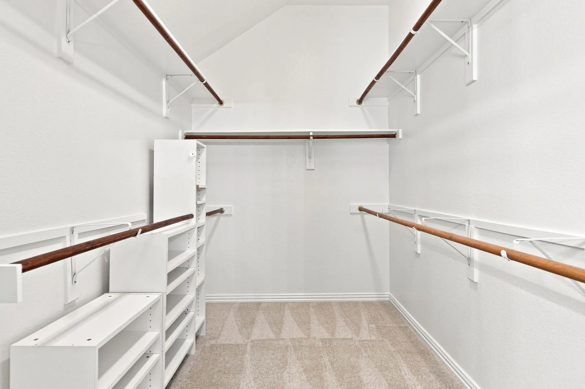 Built-in shelving units, multiple clothing rods, and textured carpeting