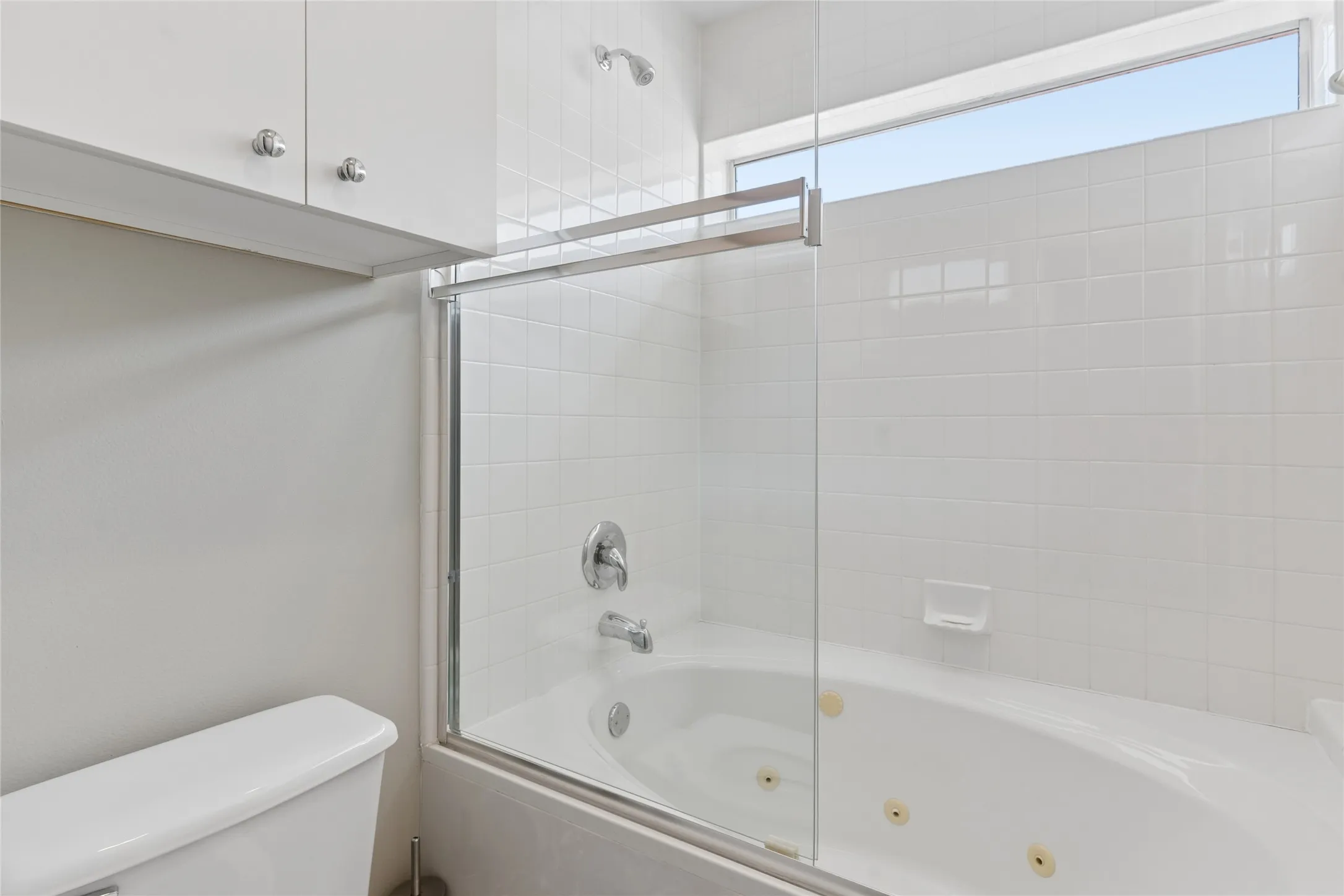 Modern bathroom featuring a frameless glass shower enclosure with chrome hardware, ceramic tile surround, and an integrated soaking tub