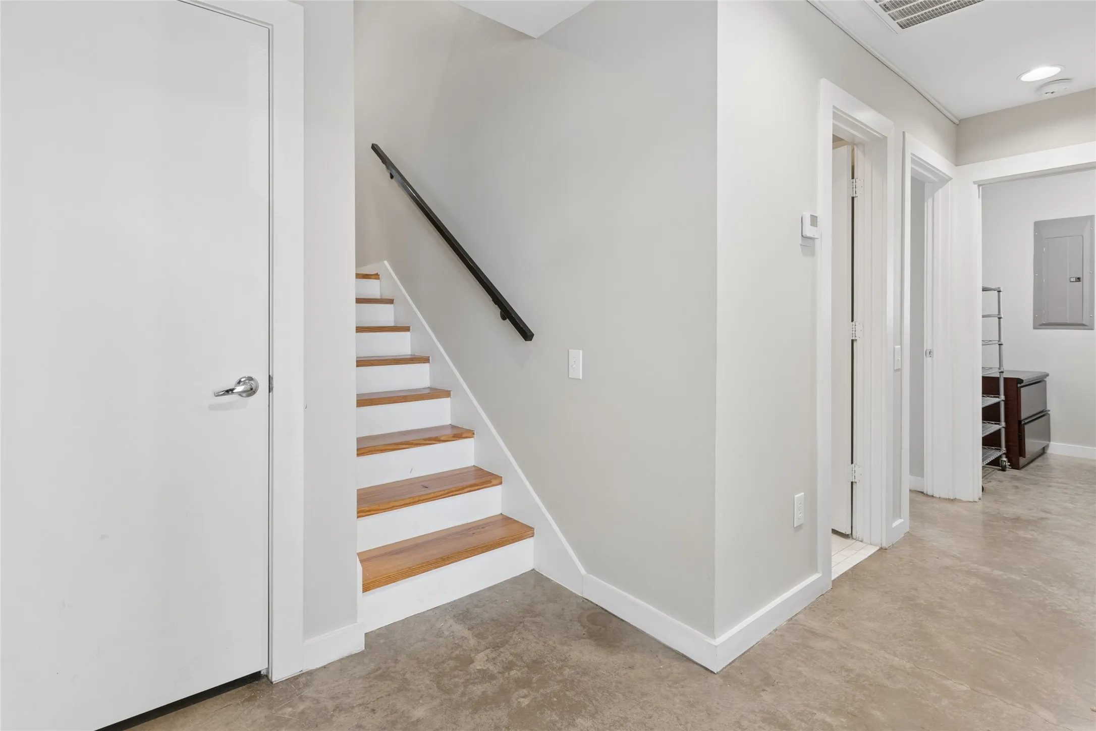 Staircase with wood-finish treads and a black handrail