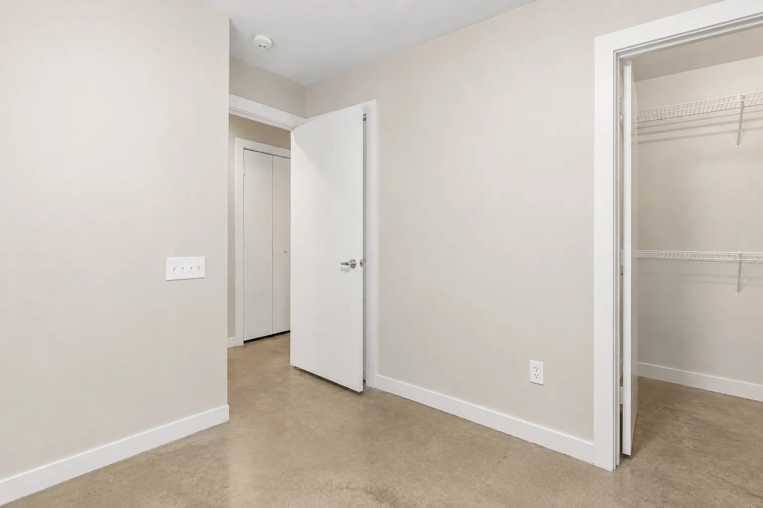 Neutral wall tones, durable concrete flooring, white trim, and a wire shelving closet system