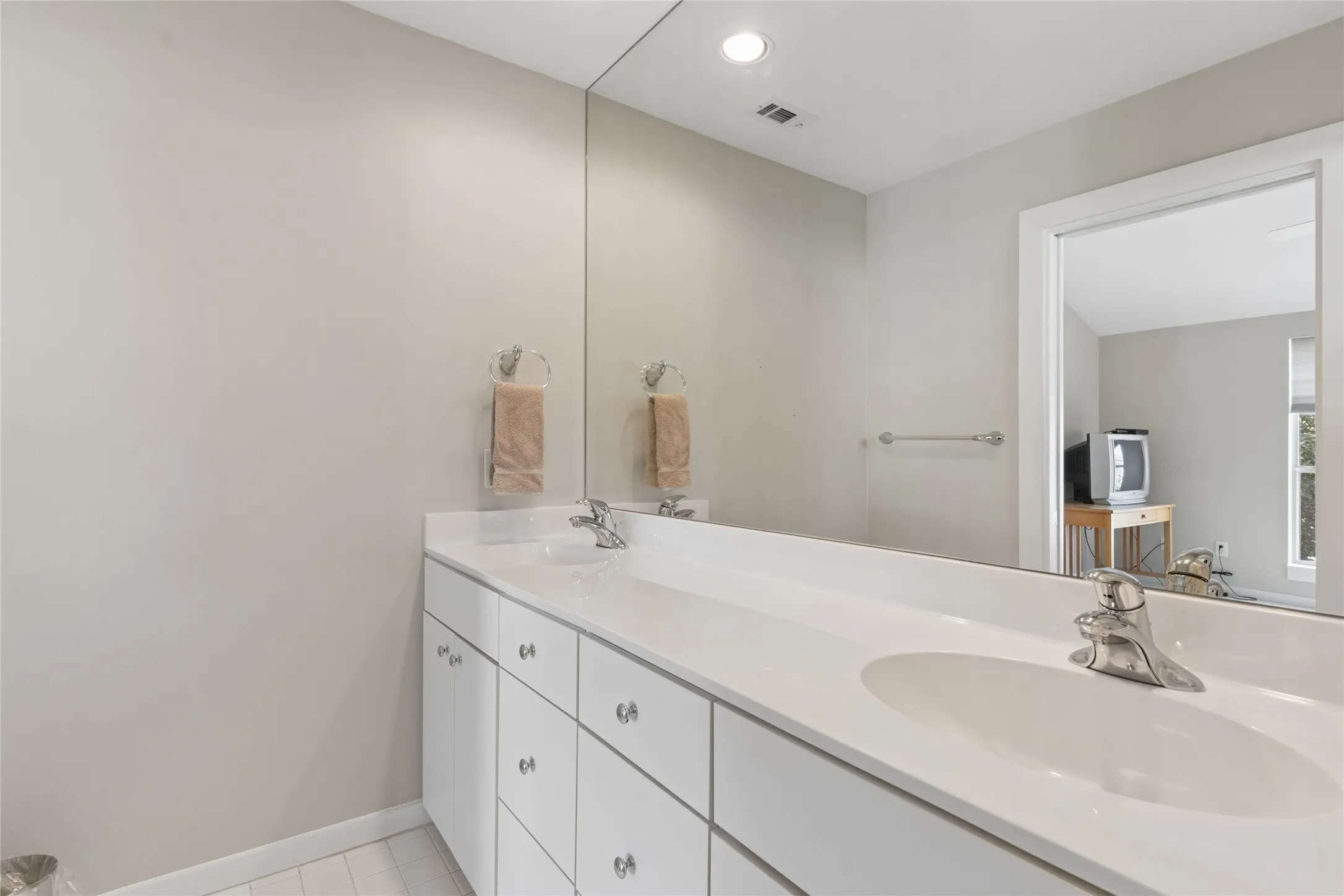 Double vanity with integrated sinks, chrome faucets, and clear cabinet hardware
