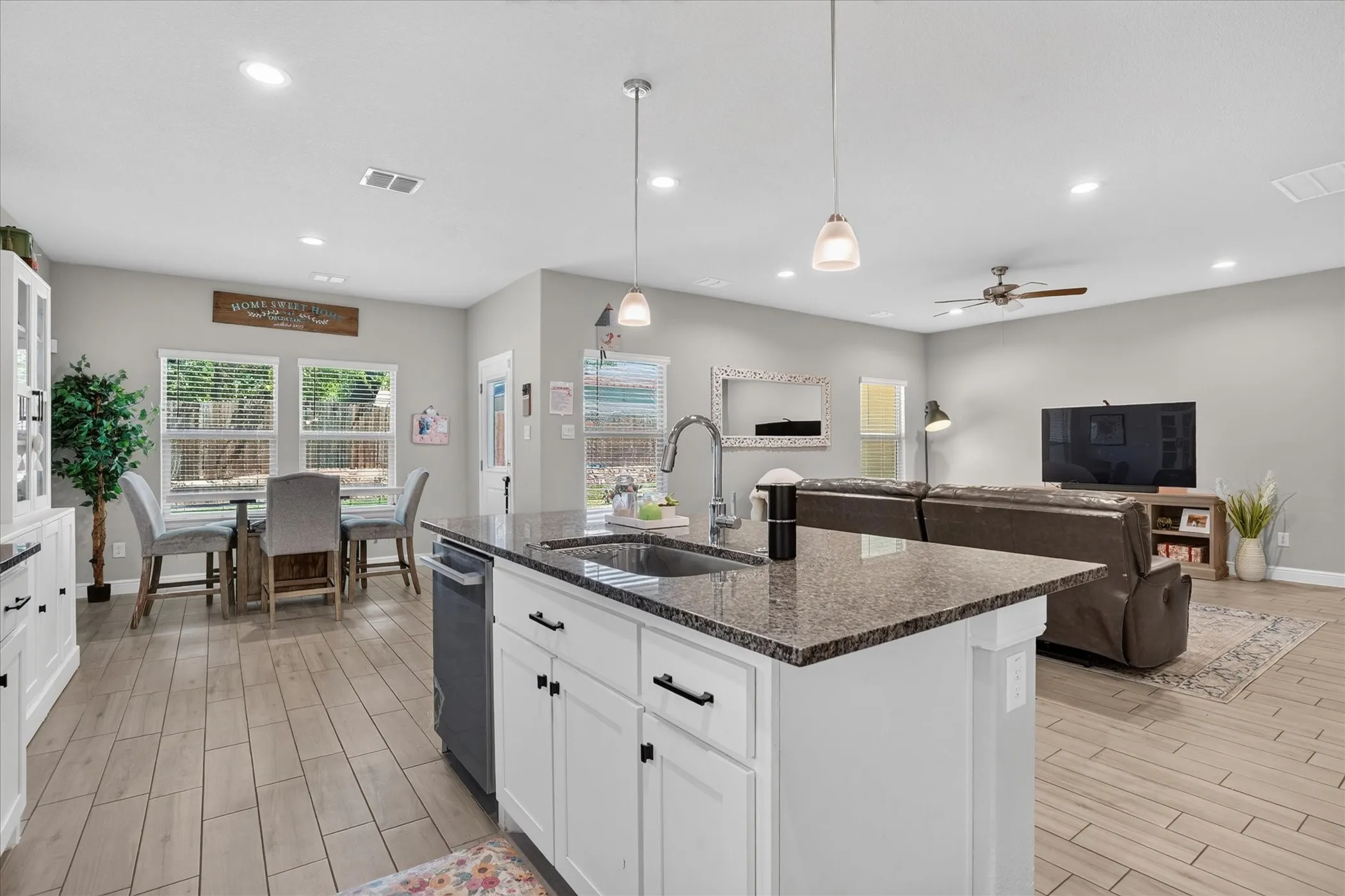 Kitchen island with granite countertop, integrated sink, and pendant lighting