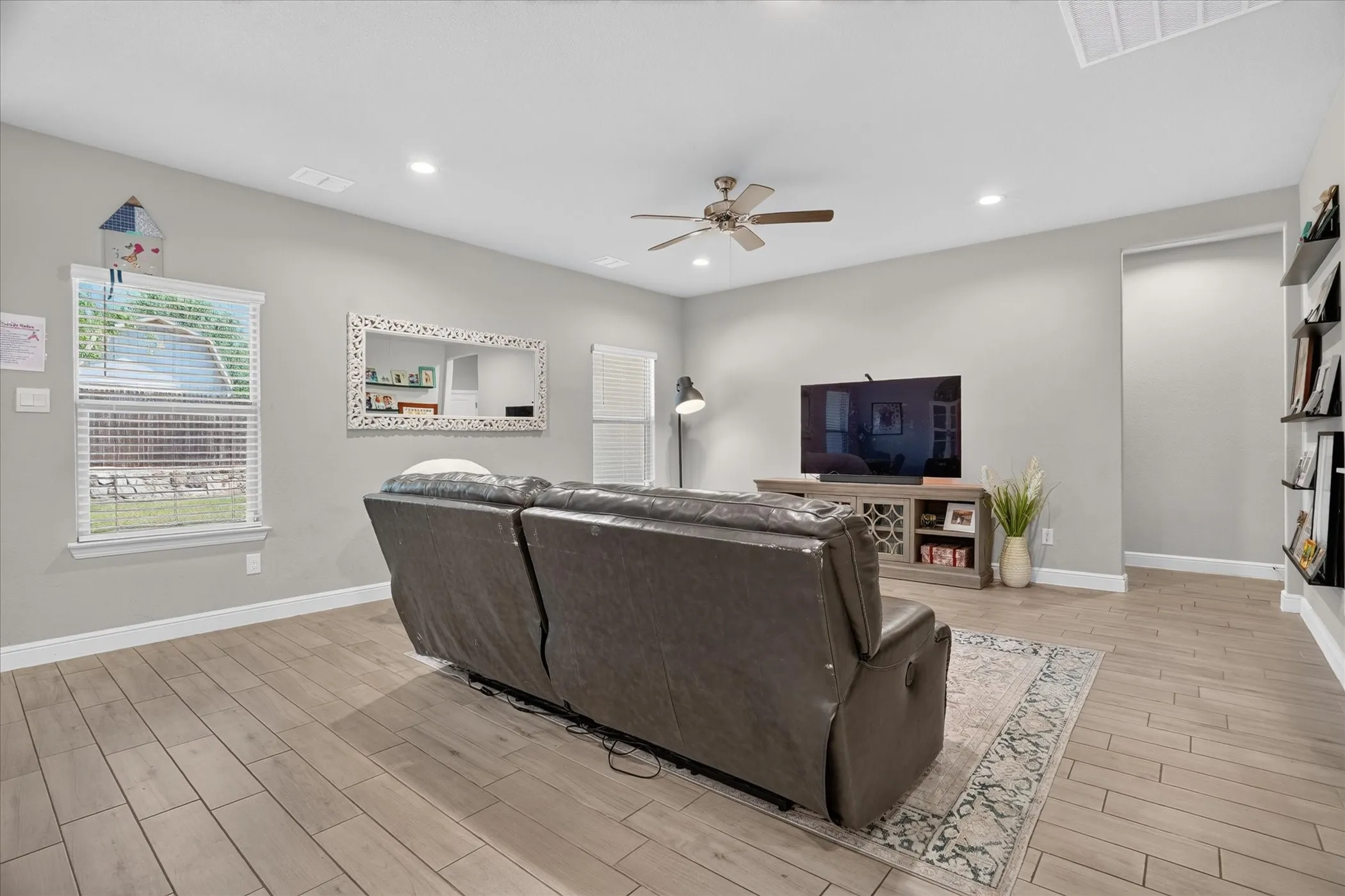 Recessed lighting, wood-finish flooring, ceiling fan, decorative floating shelves, and window with blinds