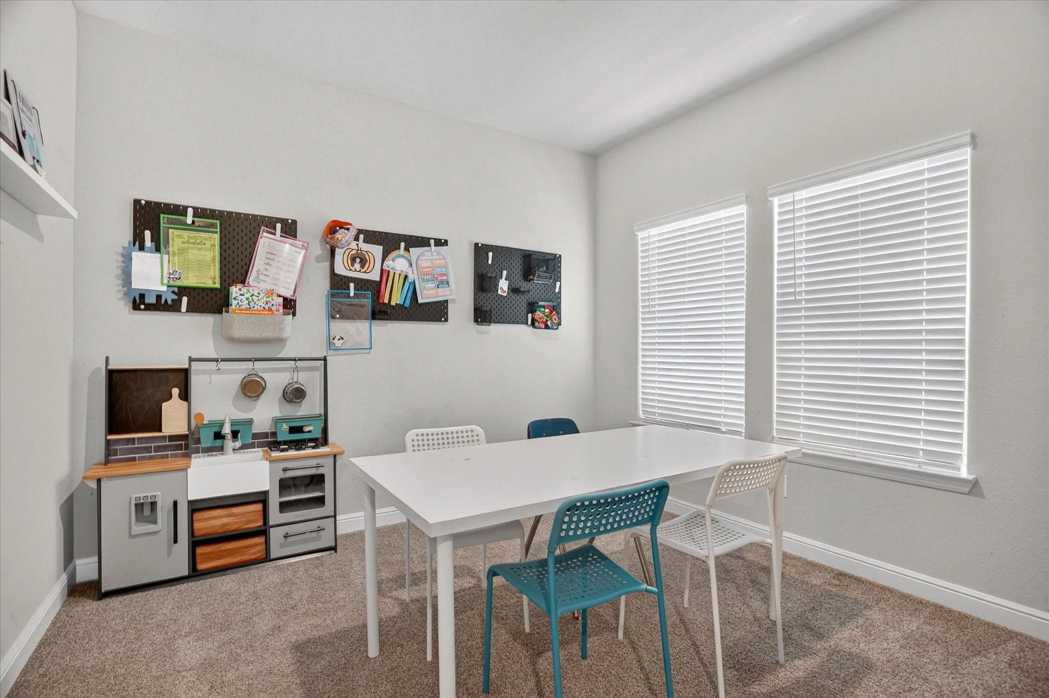 Two large windows with blinds, light gray walls, and carpeting