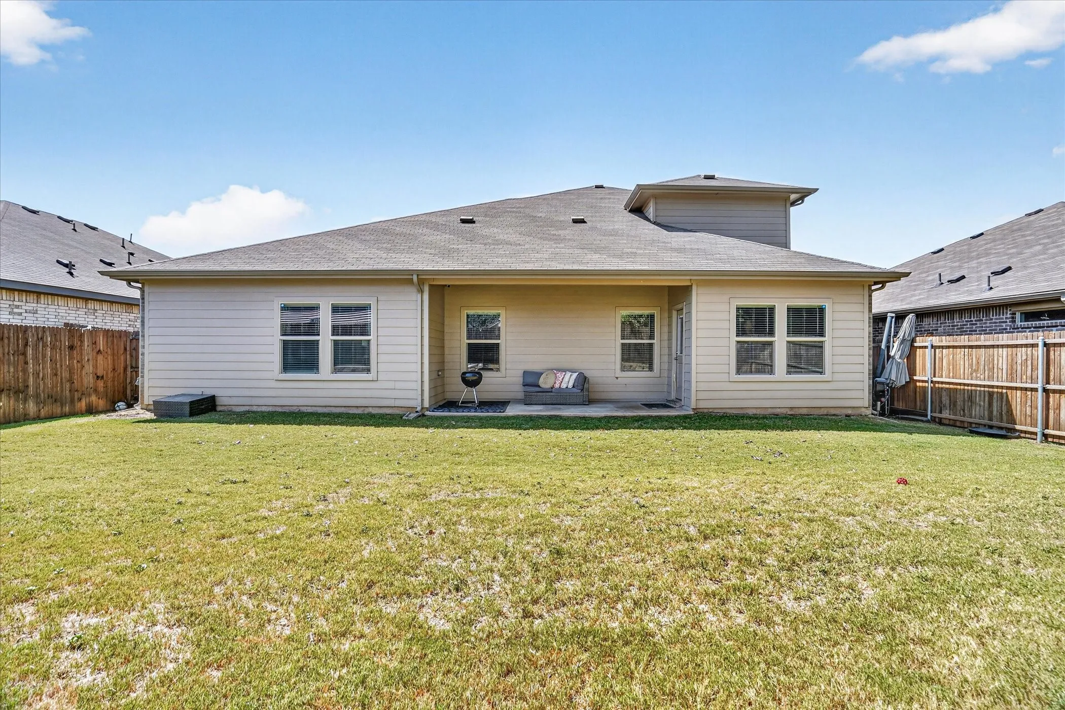 Expansive backyard featuring a manicured lawn, full fencing, and a concrete patio