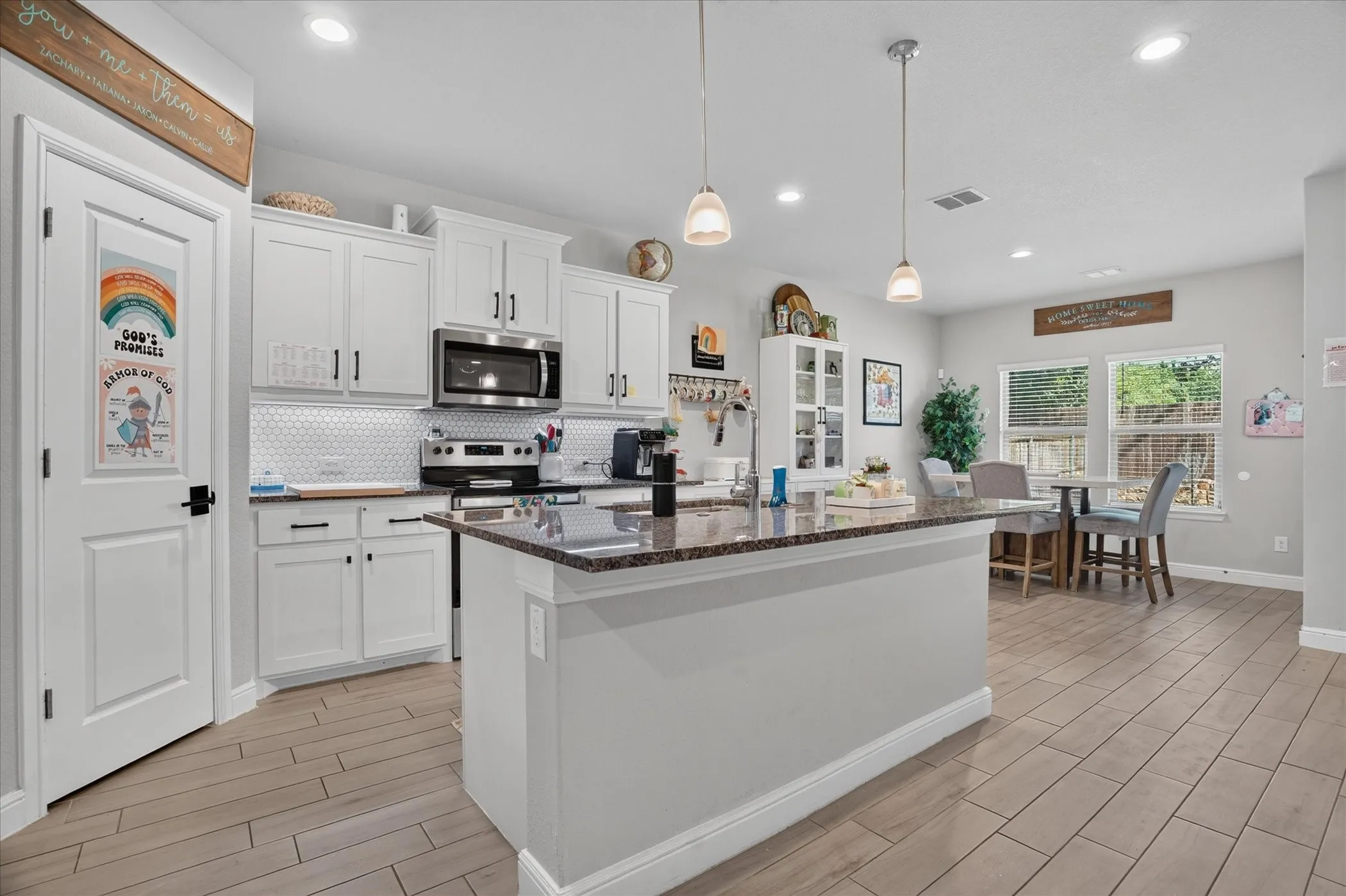 Kitchen featuring white cabinetry, stainless steel appliances, a tile backsplash, wood-finish flooring, and a stone-finish island with pendant lighting
