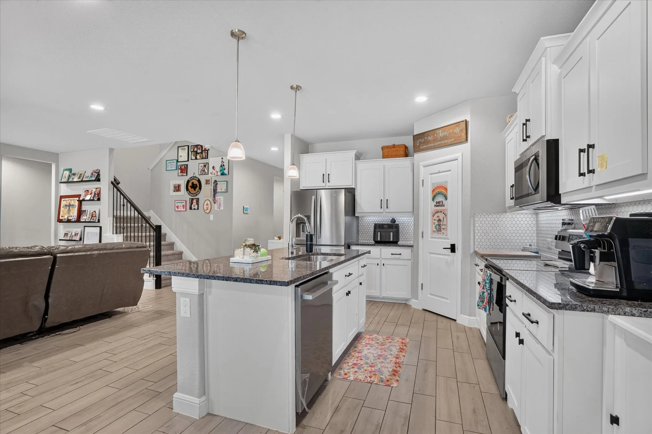 Kitchen featuring a central island with countertop, stainless steel appliances, white cabinetry, and wood-finish flooring