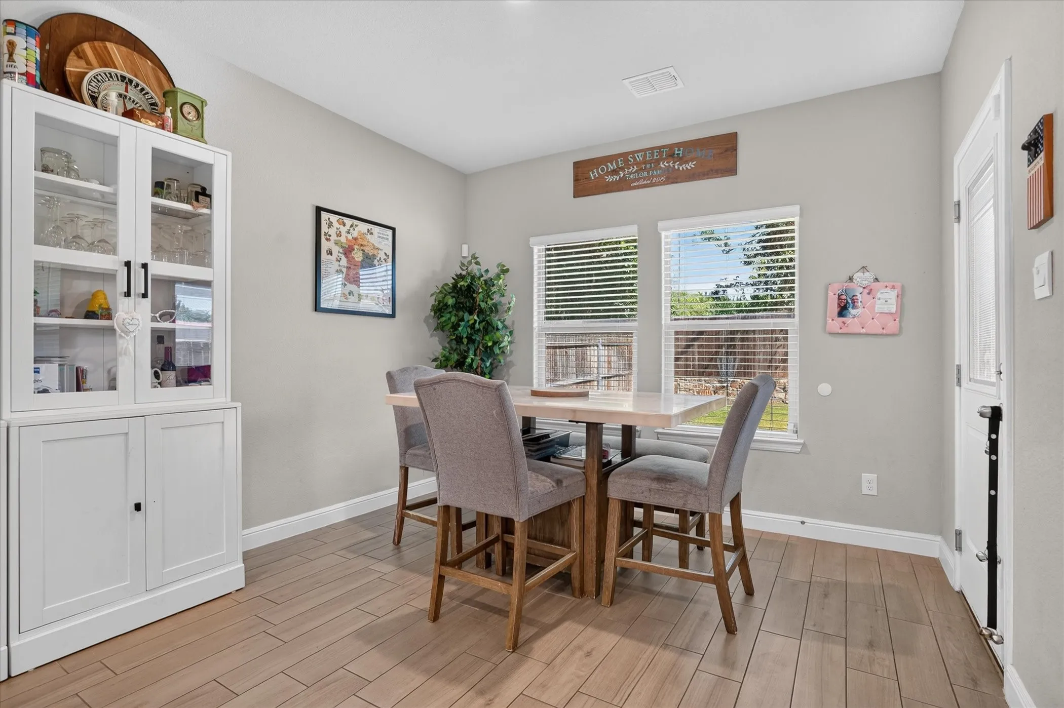 Tile flooring, neutral wall tones, two windows with blinds, and a built-in white display cabinet