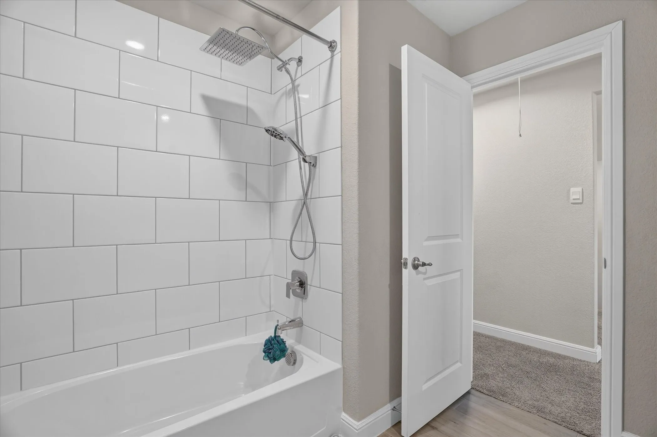 Bathtub with subway tile surround, rain shower head, and an additional handheld shower fixture
