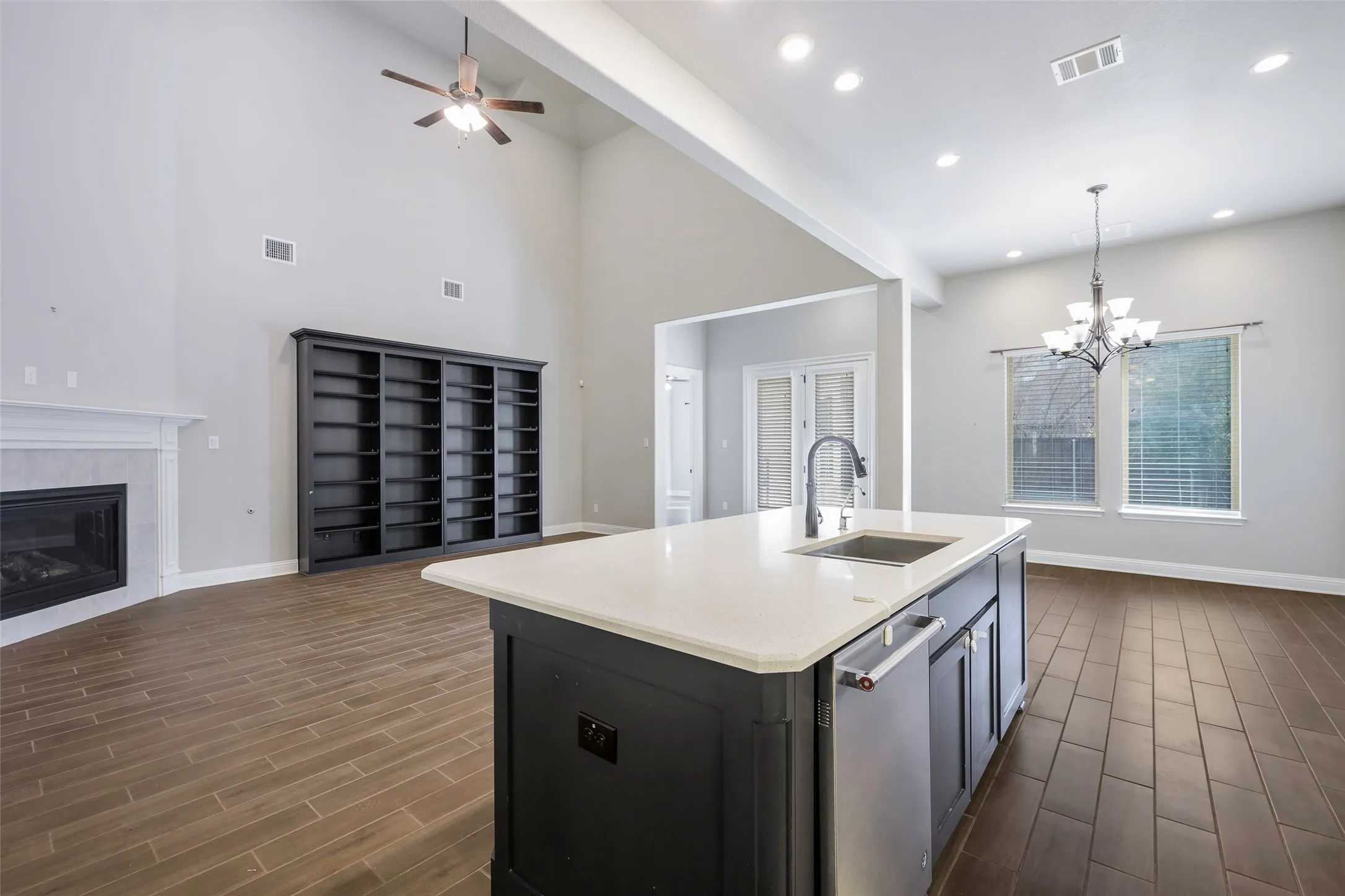 Vaulted ceilings, wood-finish flooring, built-in shelving, fireplace with mantel, kitchen island with sink and stainless steel dishwasher