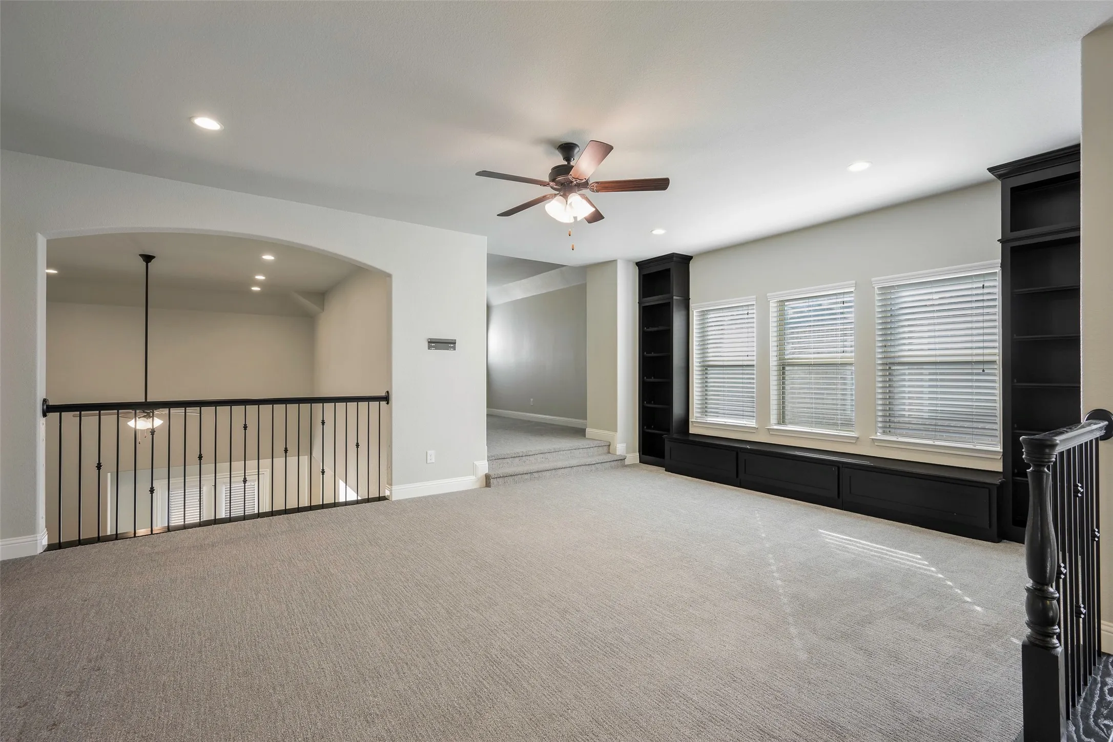Carpeted loft area featuring a ceiling fan, recessed lighting, and built-in shelving with window seating