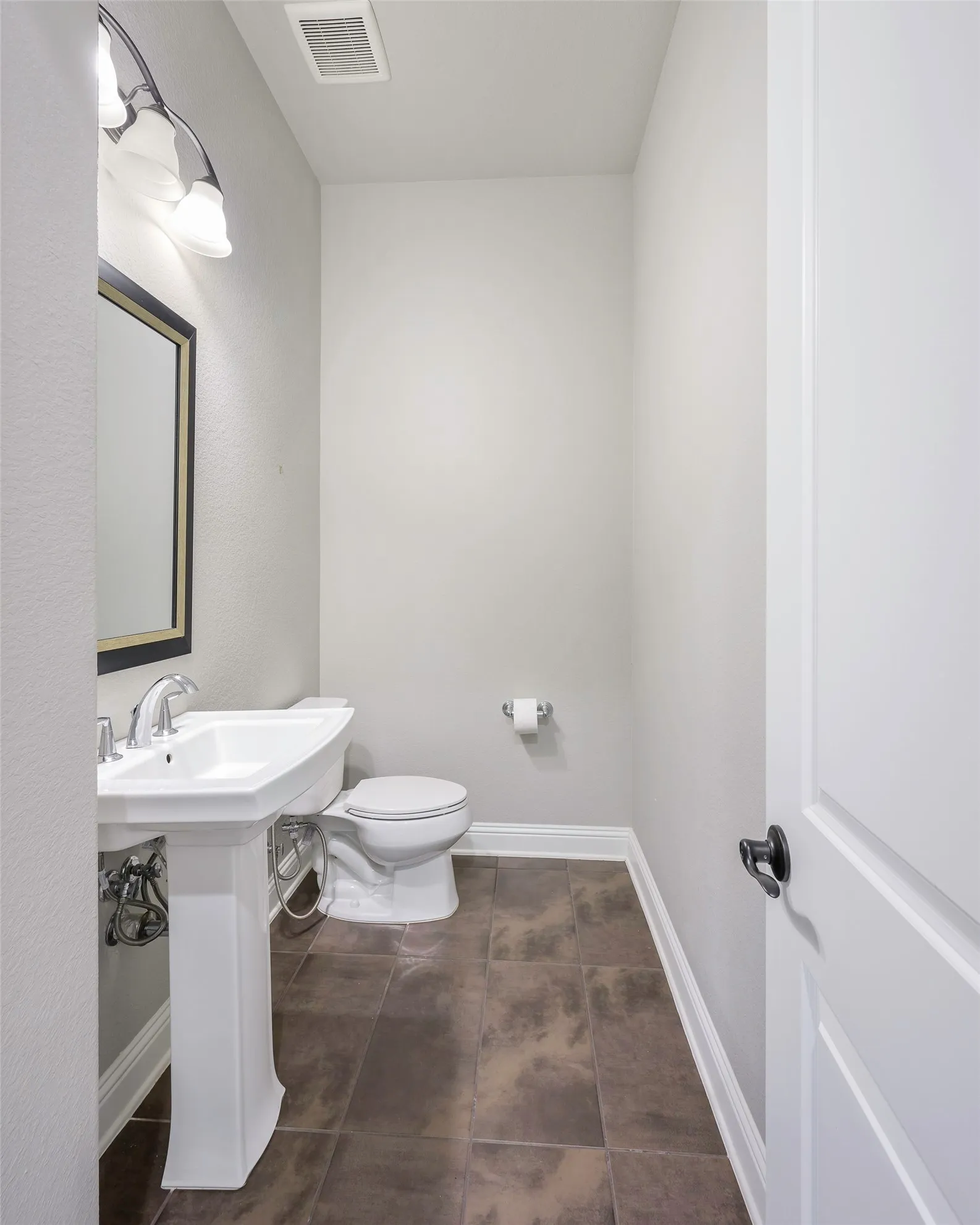 Pedestal sink with chrome faucet, square framed mirror, and rectangular floor tiles