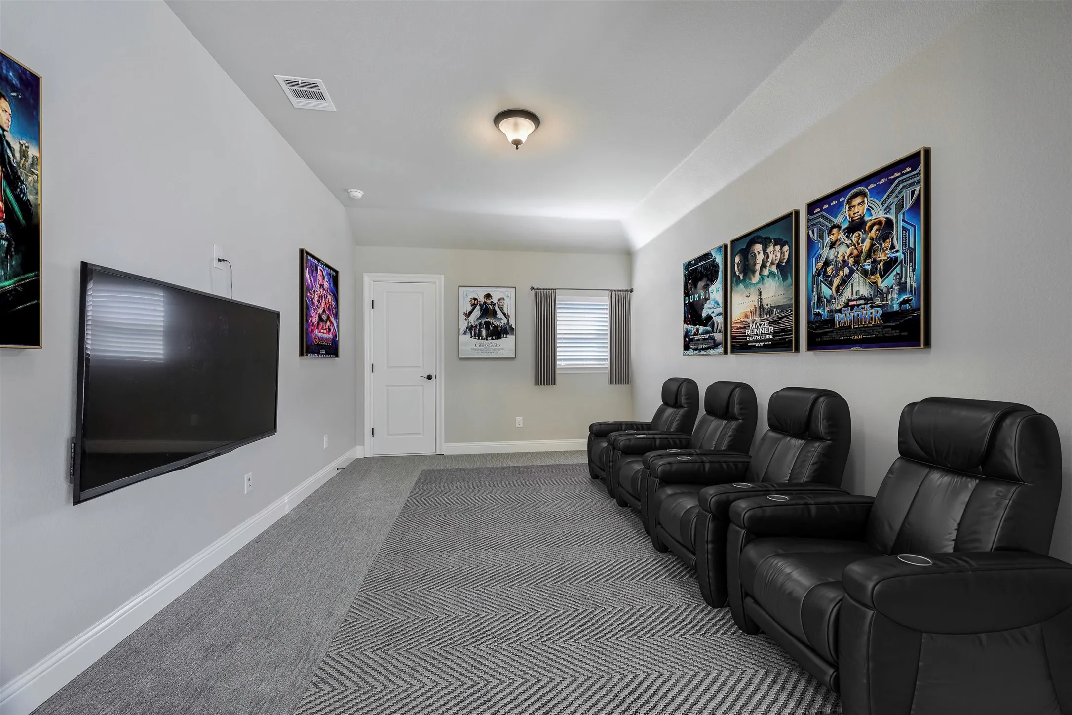 Vaulted ceiling with an attached light fixture, wall-mounted television, and a white interior door with black hardware