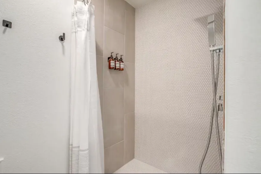 Shower featuring hexagon tile, large format wall tiles, and a chrome shower system