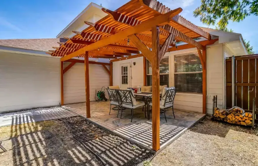 Outdoor patio with a wood pergola, stone-finish flooring, white siding, and a wooden fence