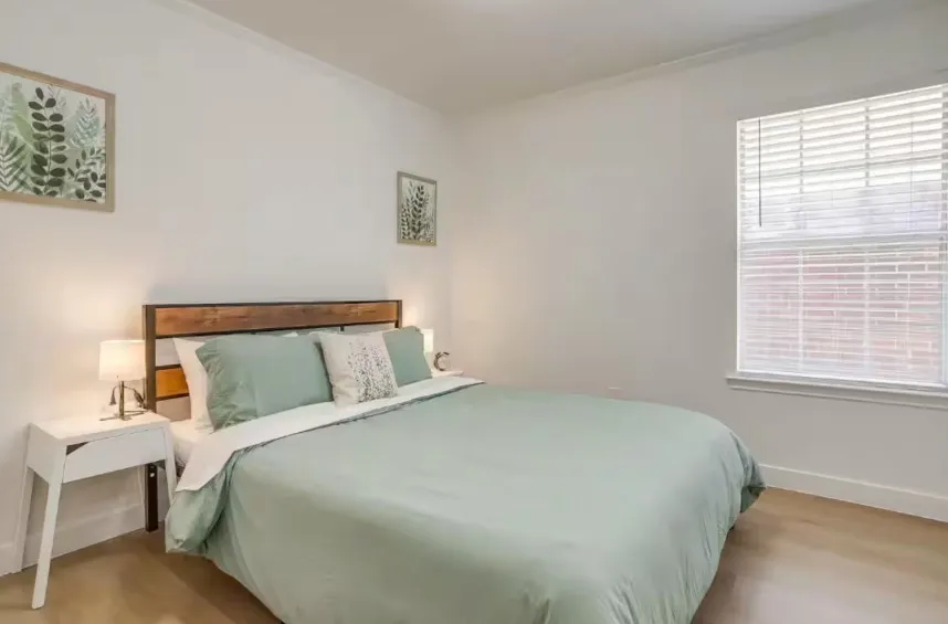 White walls with wood-finish flooring, a window featuring white blinds, and a built-in light fixture