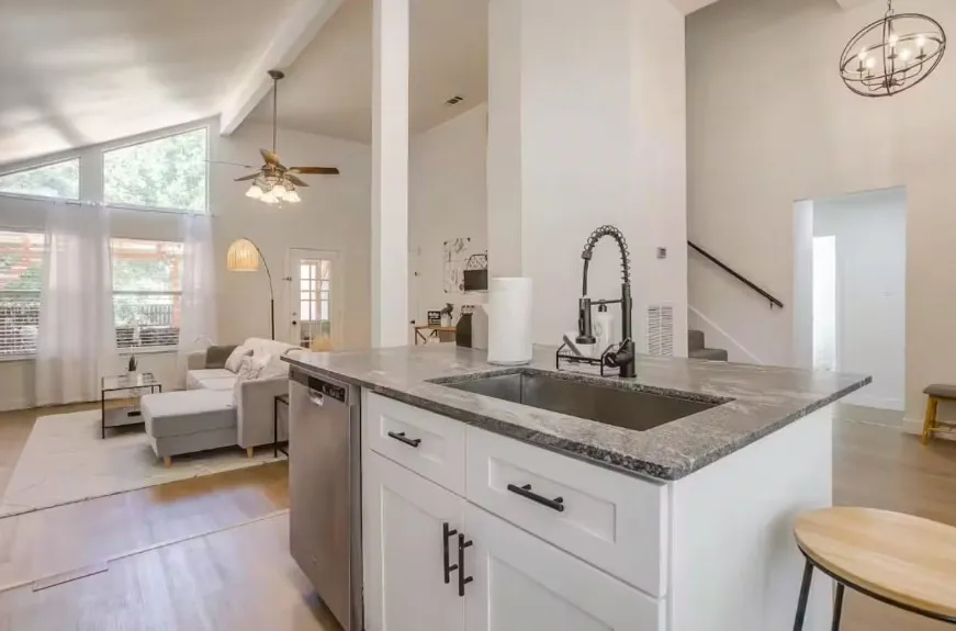 Kitchen island with integrated sink, black pull-down faucet, and white cabinetry