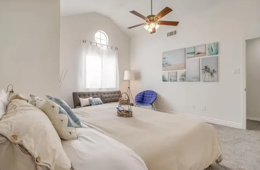 Vaulted ceiling, circular accent window, ceiling fan with integrated lighting, wall-to-wall carpeting, and a built-in upholstered headboard
