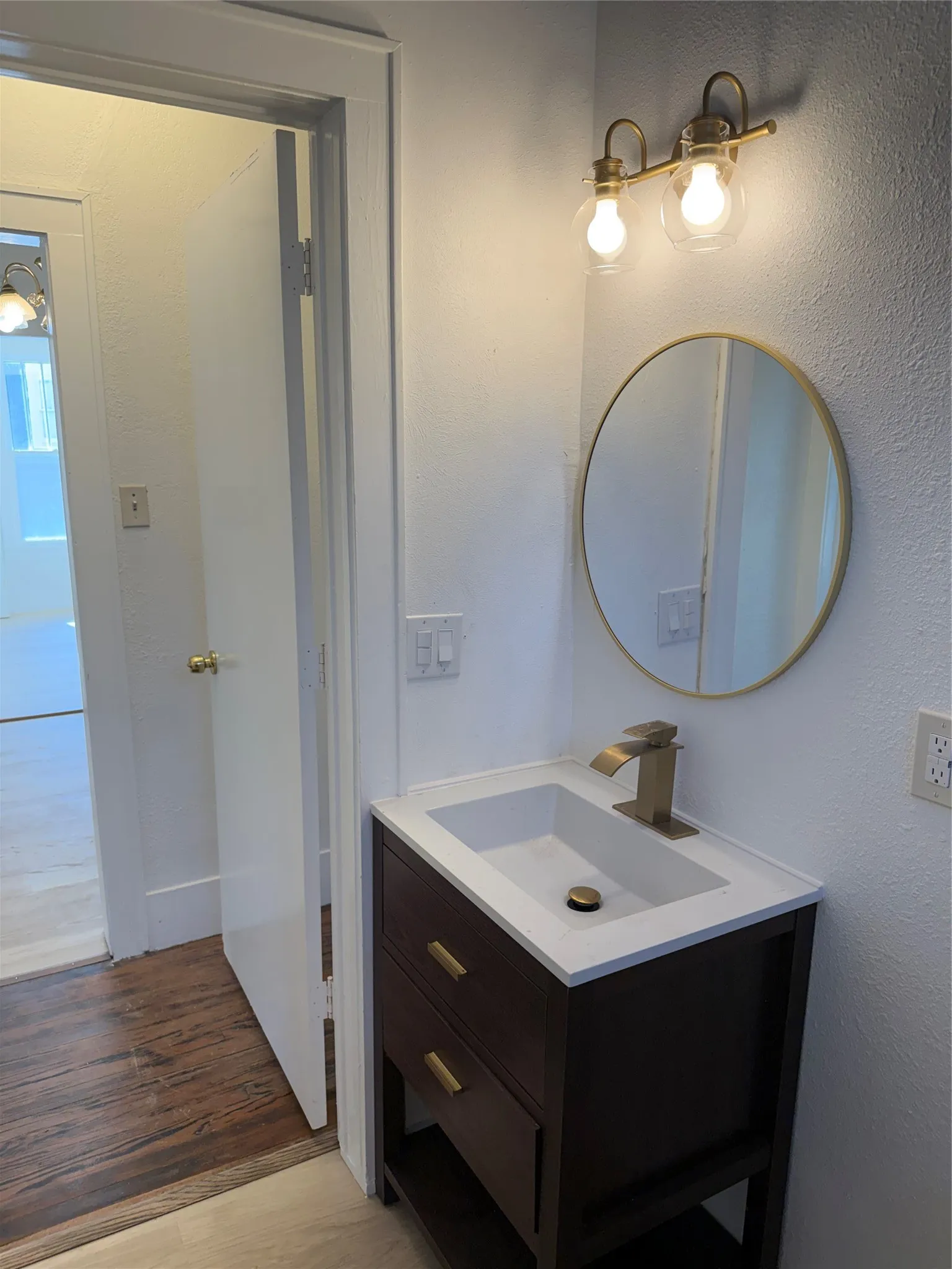 Vanity with white integrated sink, gold-finish faucet, and coordinating gold-frame mirror