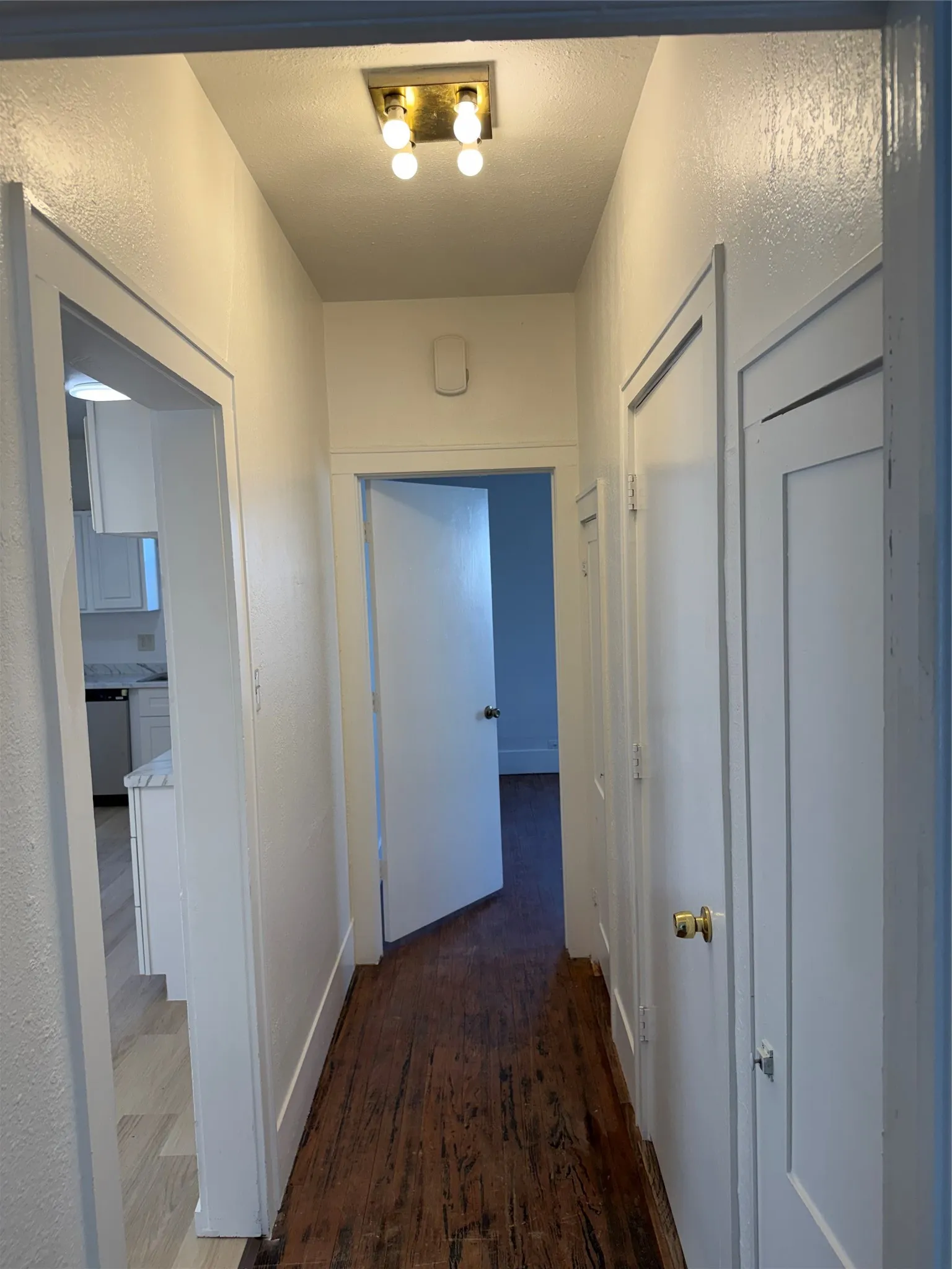 Hallway featuring wood-finish flooring, white painted walls, and a flush-mount ceiling light fixture