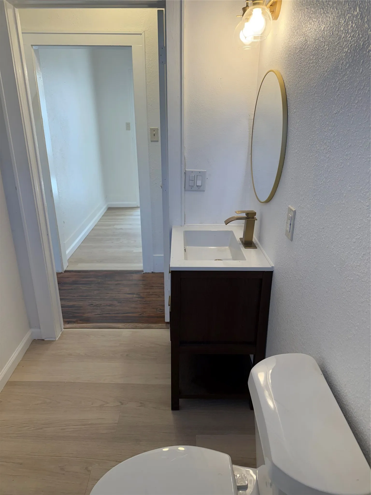Contemporary vanity with integrated sink, brass-finish faucet, and coordinating oval mirror