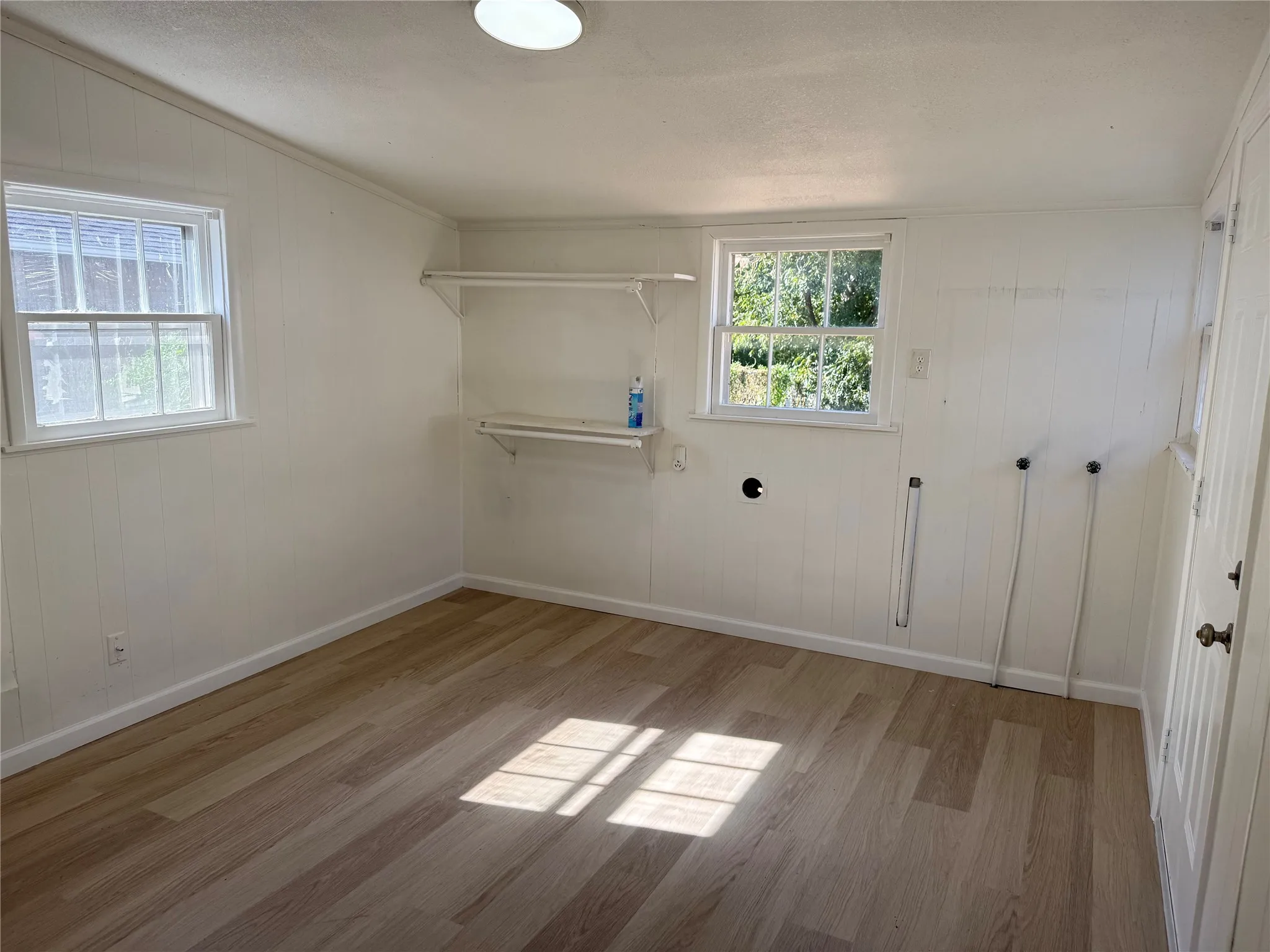 Room with wood-finish flooring, two windows, and built-in shelving