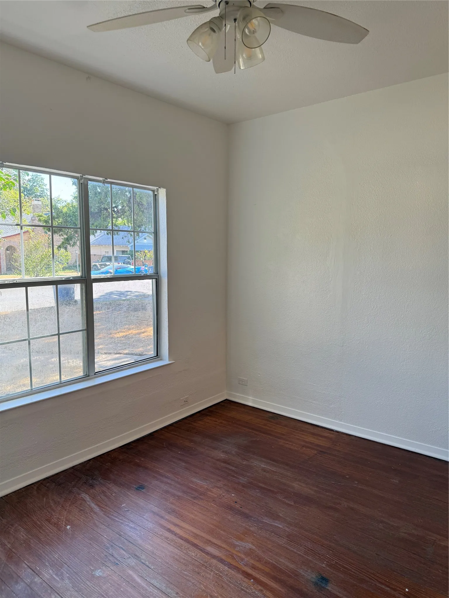 Hardwood-style flooring, white walls, and a ceiling fan with integrated lighting