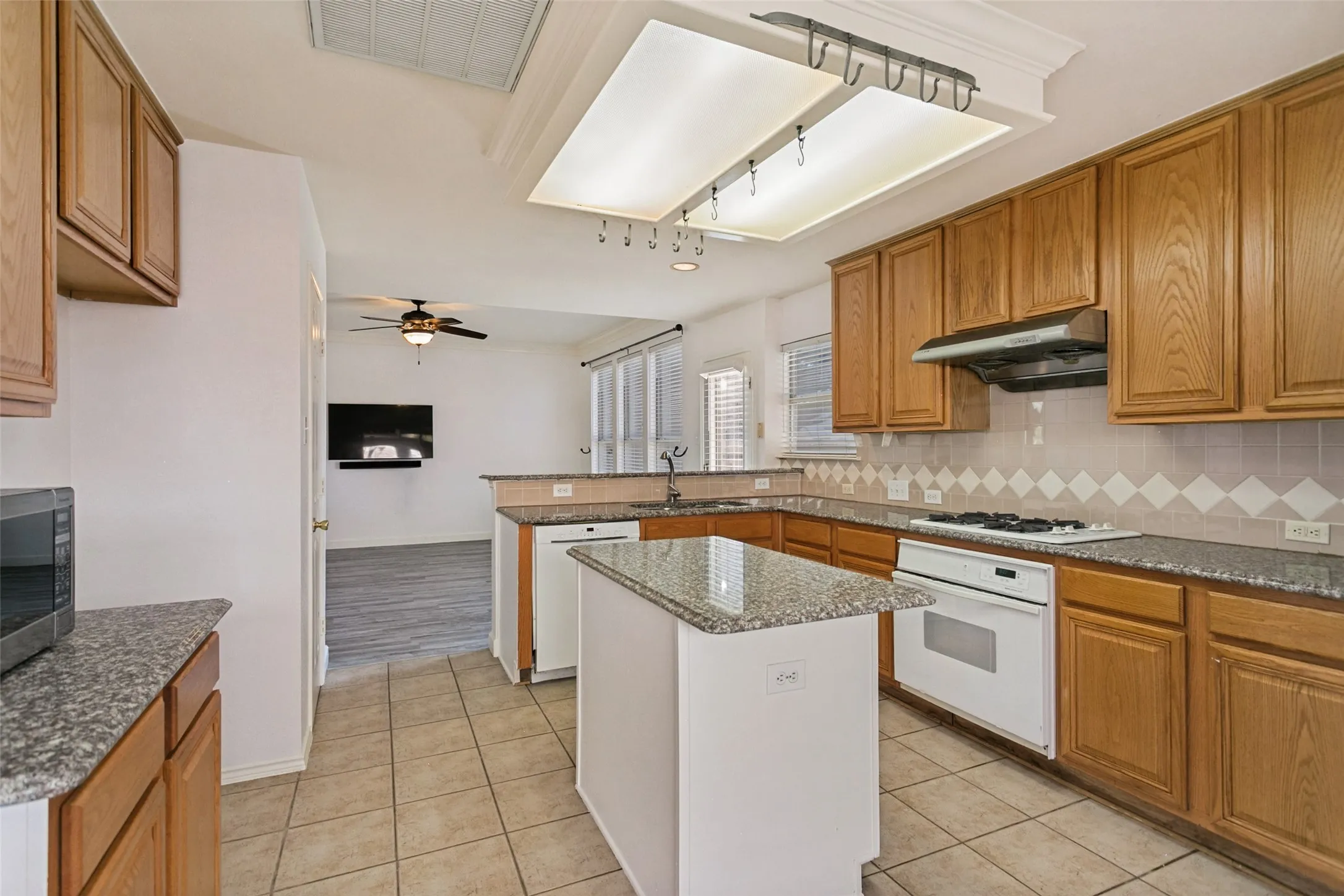 Kitchen featuring a central island with a granite countertop, wood cabinetry, tile flooring, and a white gas range